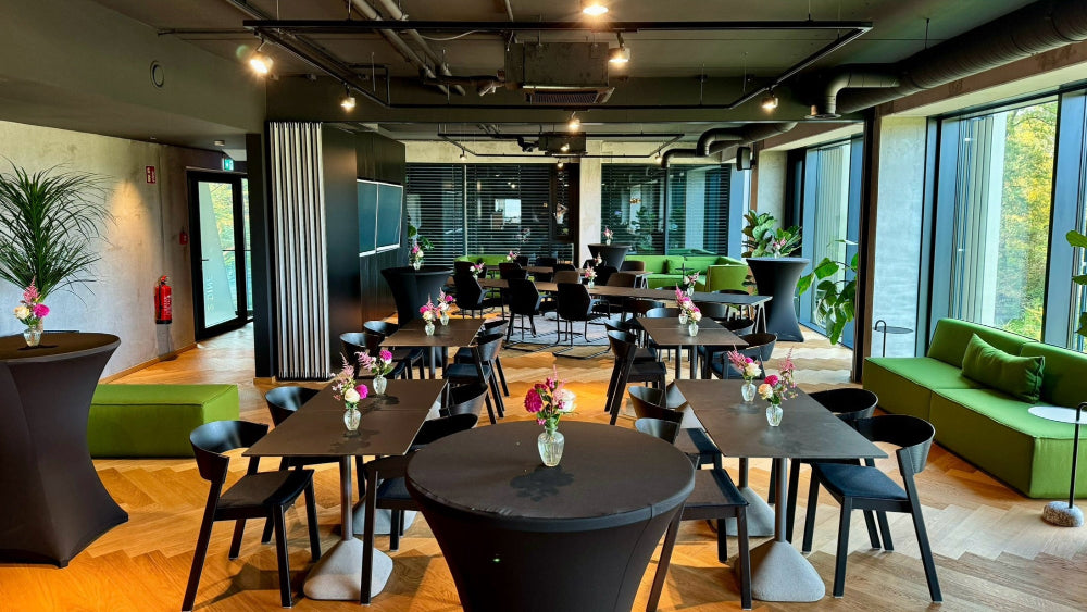 DINE im PLICANA mit schwarzen Tischen, schwarzen Stühlen und grünen Sofas