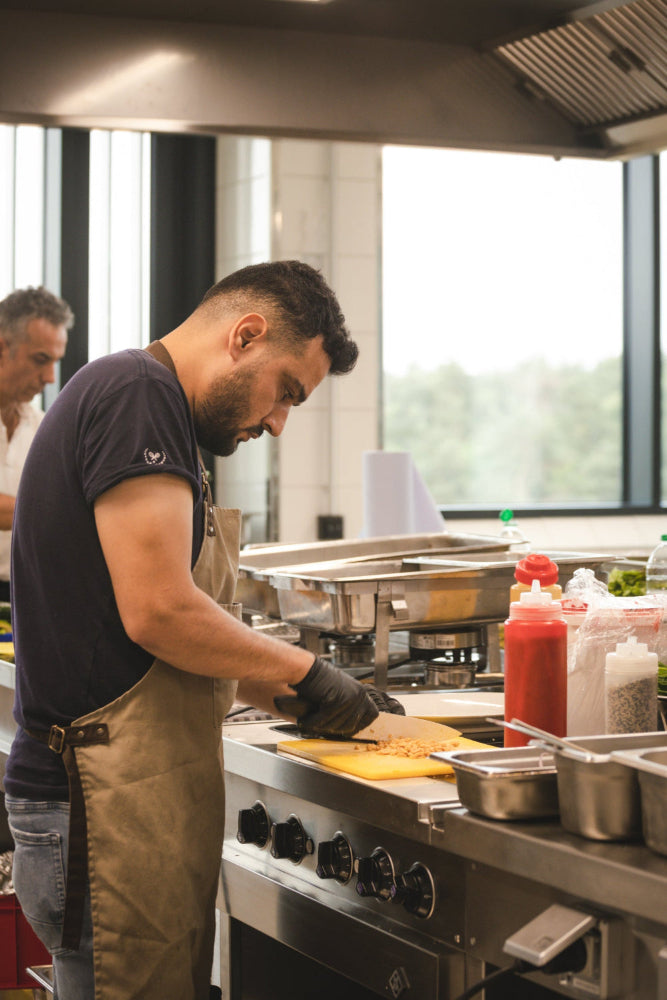 In der Küche des PLICANA in Kronau wird gemüse geschnitten von einem Mann mit Kochschürze