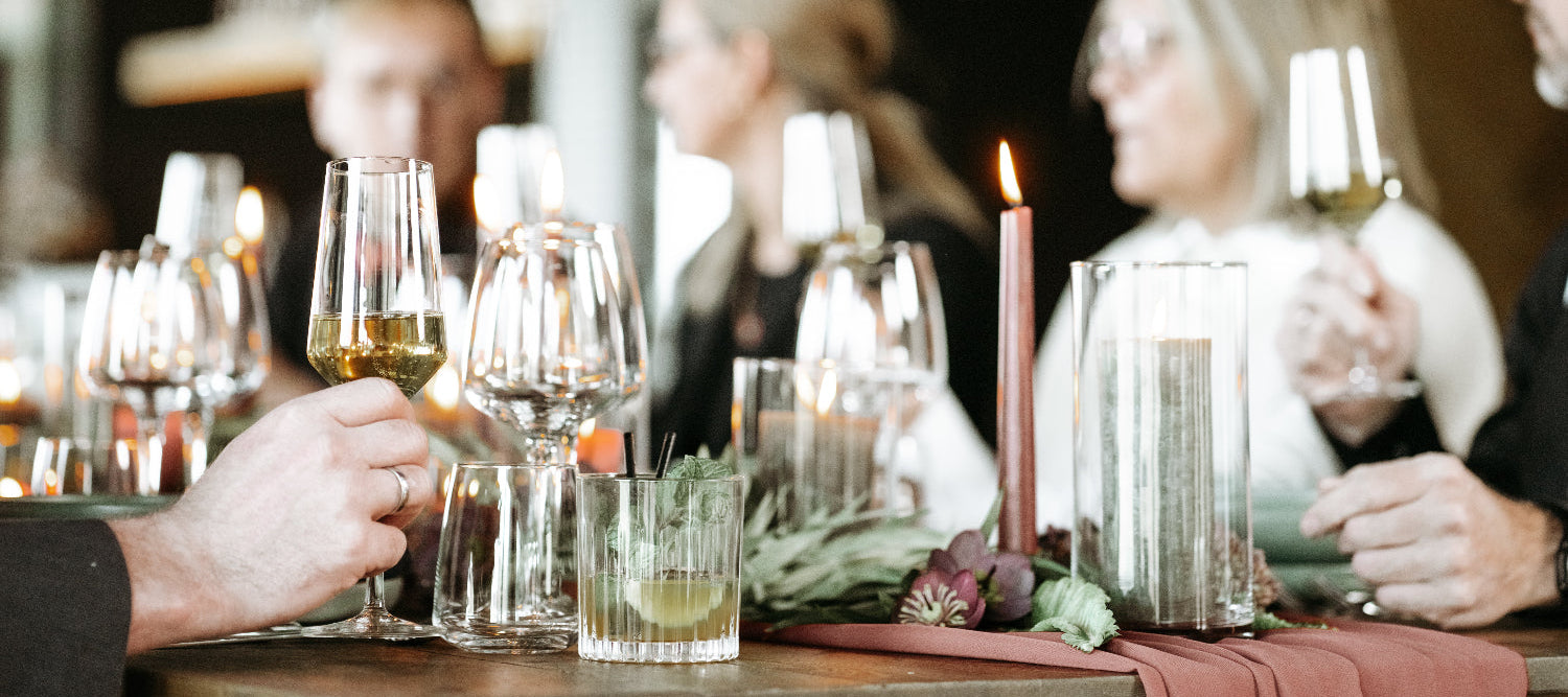 Menschengruppe mit Sektgläsern an Tisch mit Weihnachtsdeko